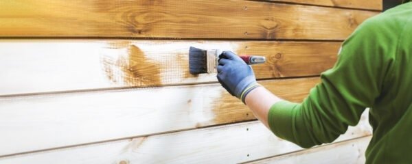 A painter repainting a wood wall white