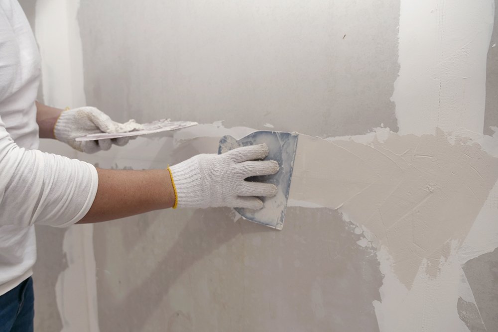 A professional fills a hole in drywall and preps it for painting