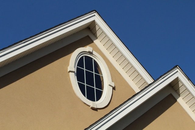 A painted stucco home exterior with a round window