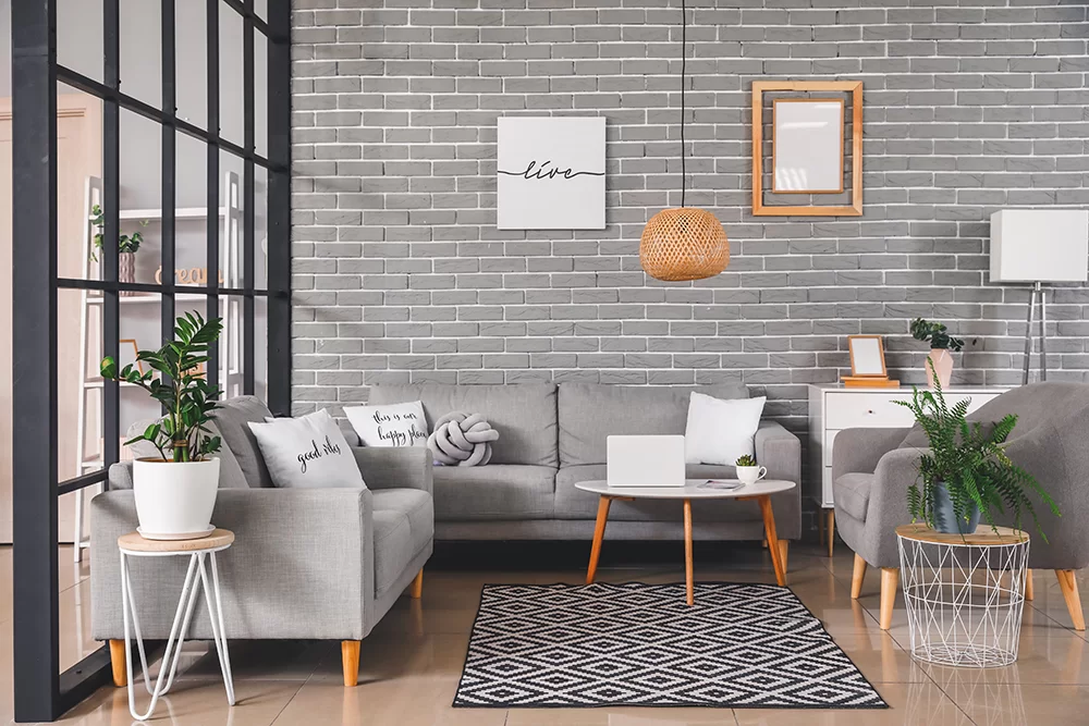 A gray-painted brick living room interior with gray and natural furniture
