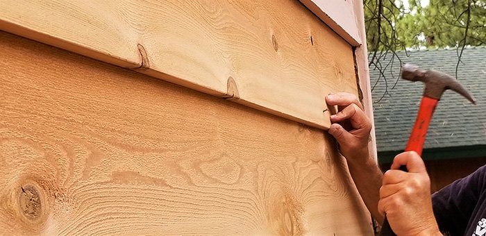 A professional performs repairs on wooden siding