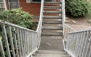 Metal railings with cracked white paint accompanying concrete outdoor stairs