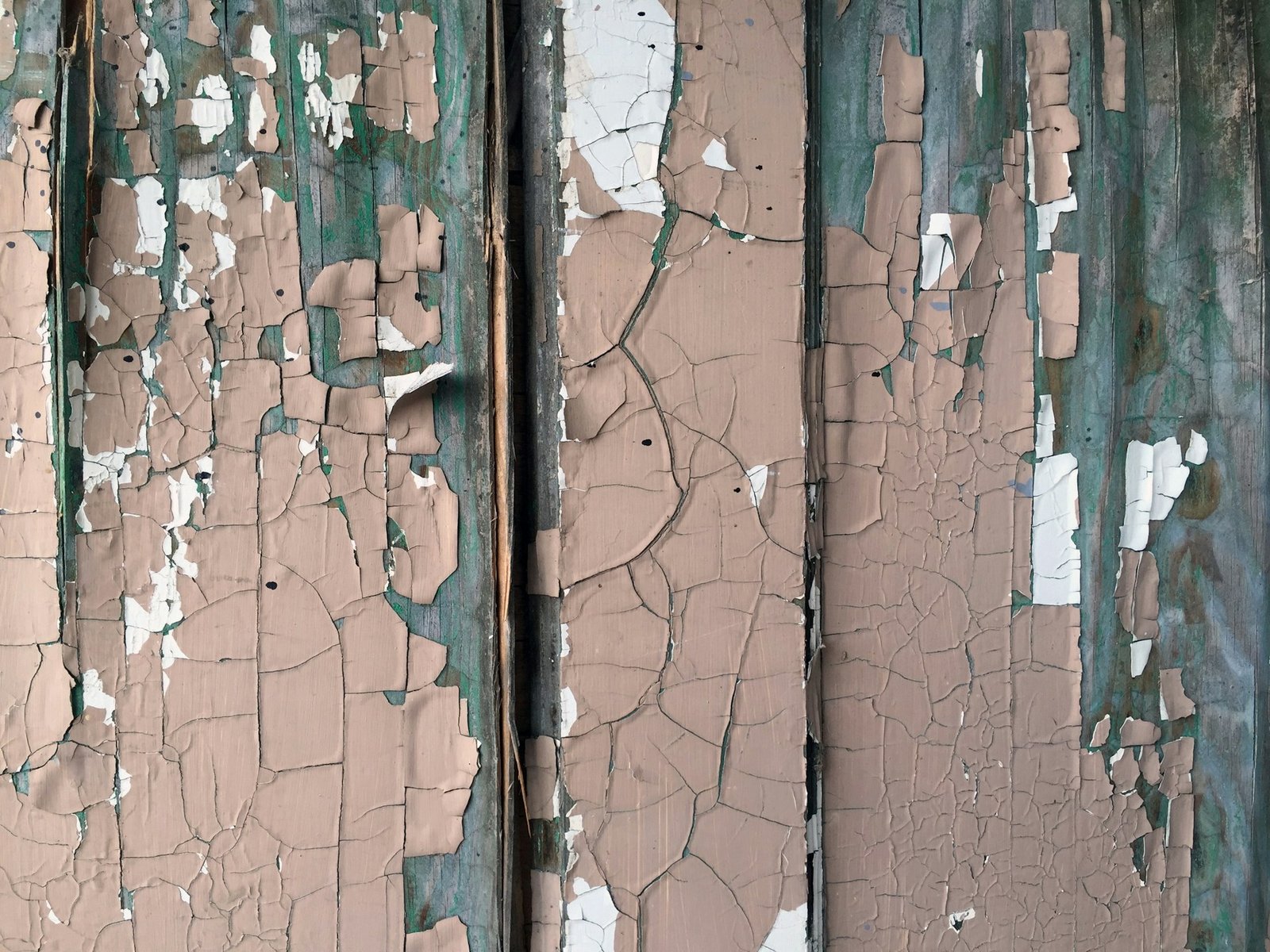 A layer of cracked and peeling brown paint on a wooden surface