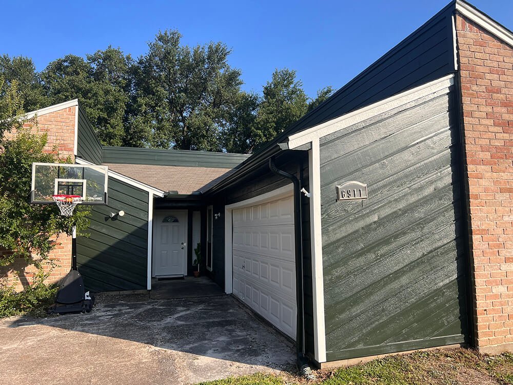 A brick house with dark green-painted woood siding features