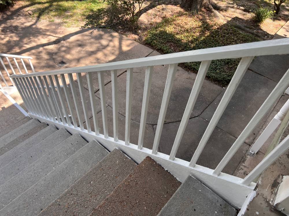 A freshly painted railing attached to concrete stairs