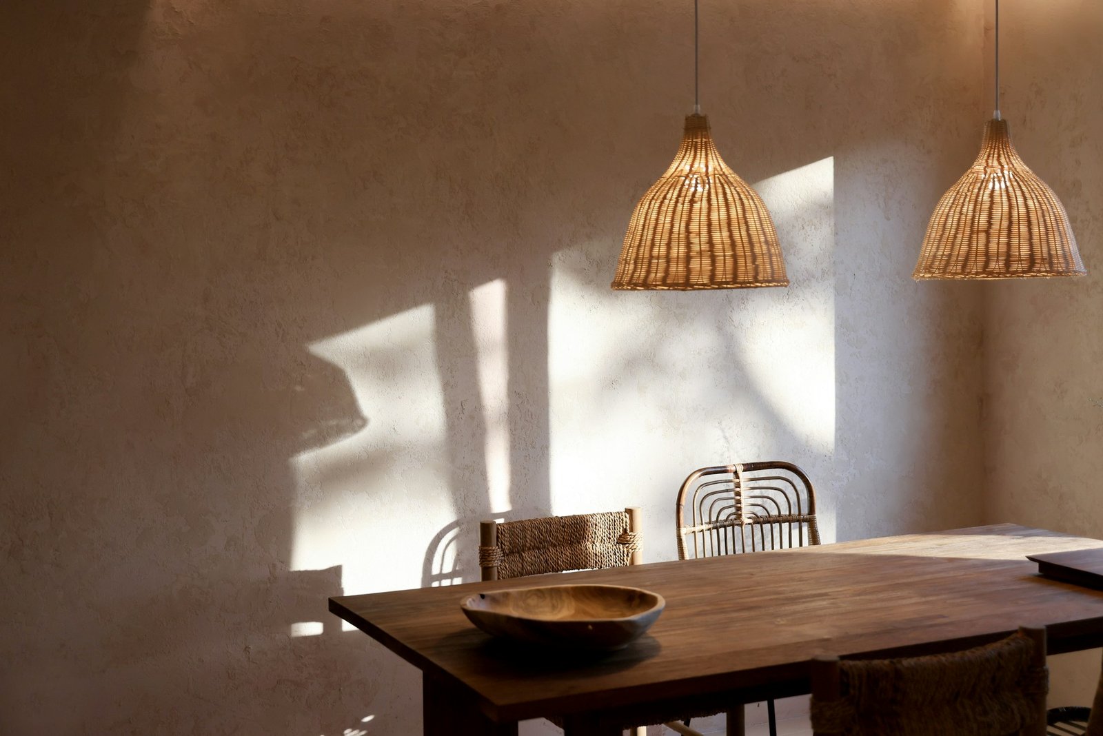 A dining room with beige limewash walls and a wooden table