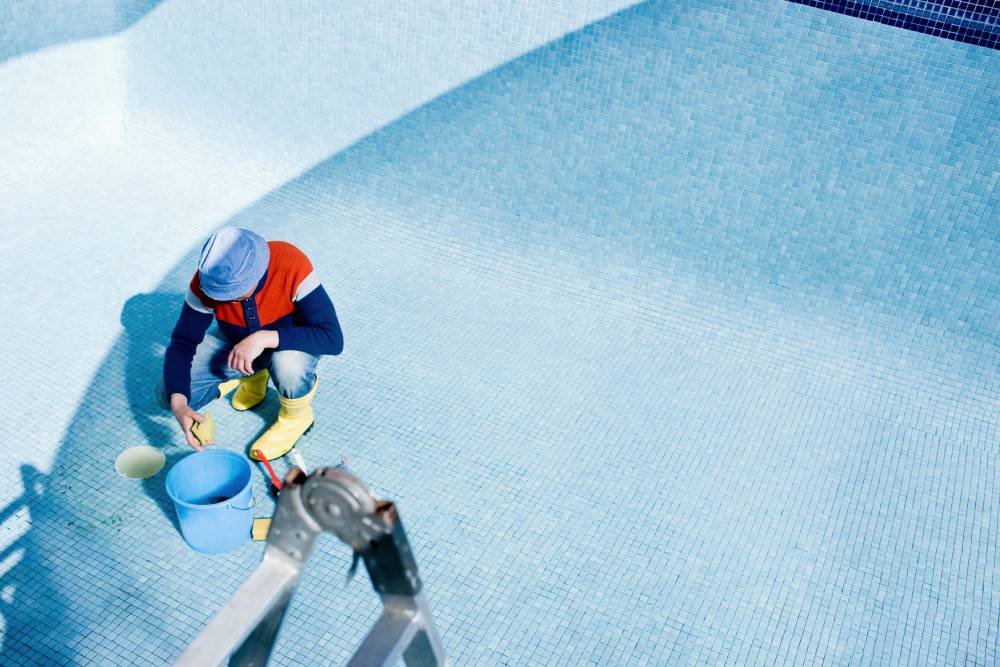 A man cleans the pool floor in preparation for painting