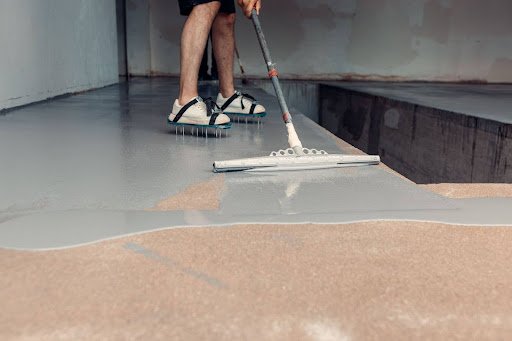 Professional flooring contractor spreading epoxy on a large garage floor