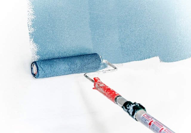 blue-interior-wall-paint-roller Blue paint being rolled onto interior wall