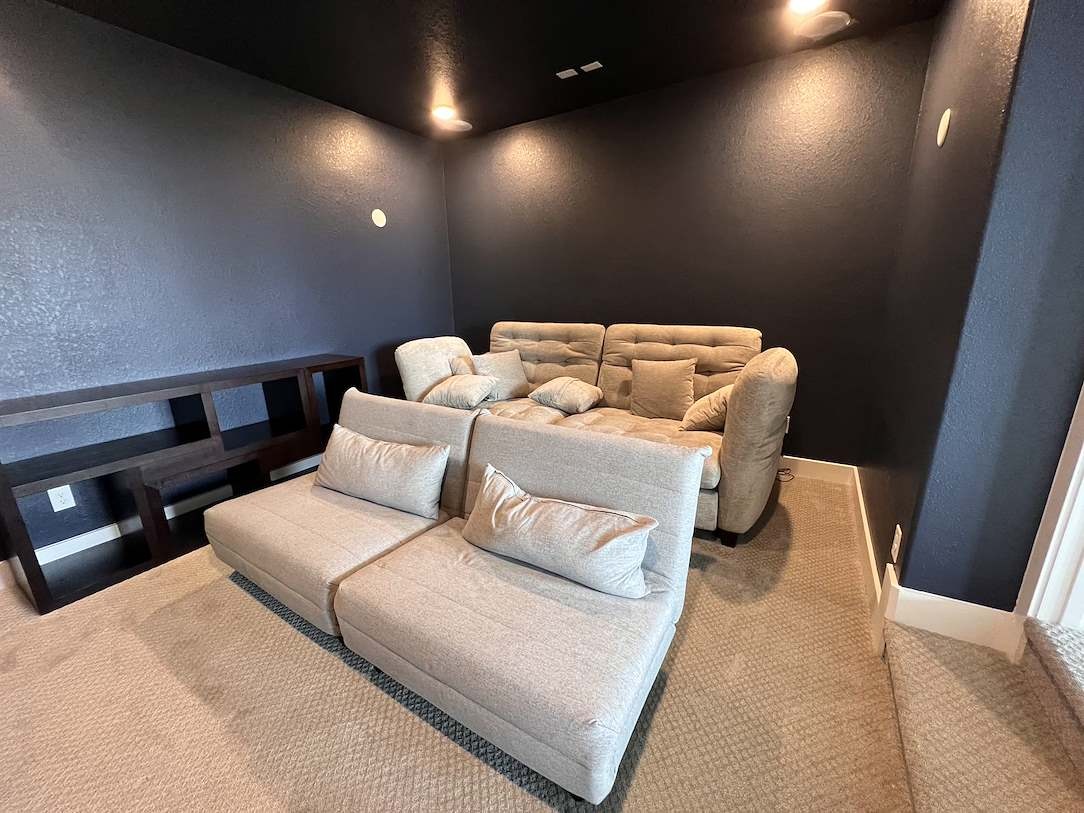 home-painters-clear-lake A home theater interior with dark painted walls, light-colored sofas, and recessed lighting